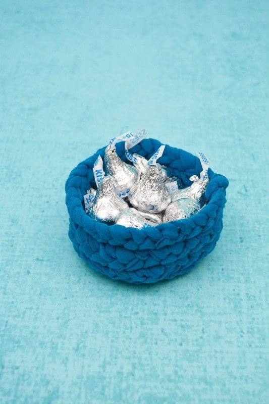DIY storage baskets from old clothes with a braided t-shirt yarn bowl in blue holding wrapped chocolates